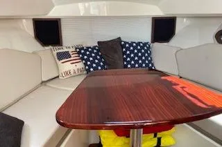Slide: The Image of 2019 Pursuit OS 325 Offshore cabin with star-themed cushions and wooden table. - 19