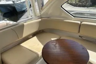 Slide: The Image of 2019 Pursuit OS 325 Offshore boat interior with beige seating and wooden table. - 21