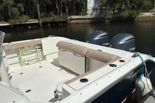 Slide: The Image of 2019 Pursuit OS 325 Offshore boat with dual engines docked by a wooded shoreline. - 3