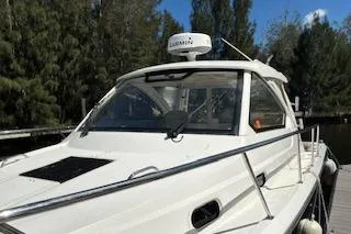 Slide: The Image of 2019 Pursuit OS 325 Offshore boat docked near trees under a clear blue sky. - 4