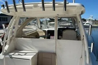 Slide: The Image of 2019 Pursuit OS 325 Offshore boat docked, featuring spacious cockpit and rod holders. - 7