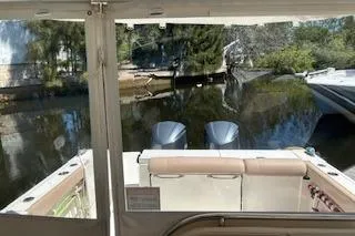 Slide: The Image of 2019 Pursuit OS 325 Offshore boat with dual engines, docked near a serene waterway. - 8