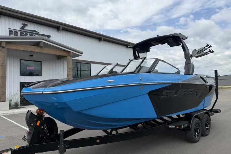 Slide: The Image of 2026 Supra SA boat in vibrant blue on trailer, parked outside a modern building. - 3