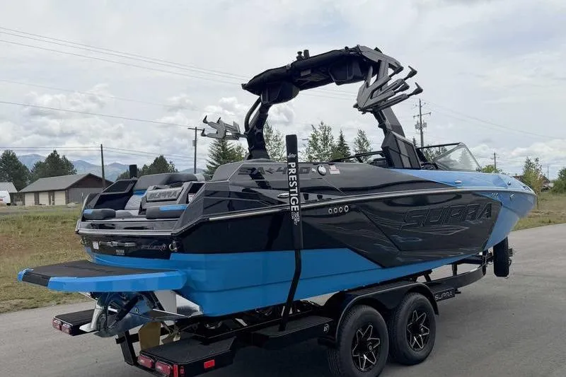 Slide: The Image of 2026 Supra SA boat on trailer, blue and black design, parked outdoors. - 10
