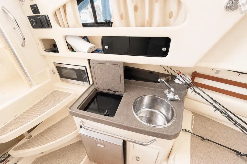 Slide: The Image of 2007 Grady-White Marlin 300 interior with kitchenette, sink, and fishing rods. - 9