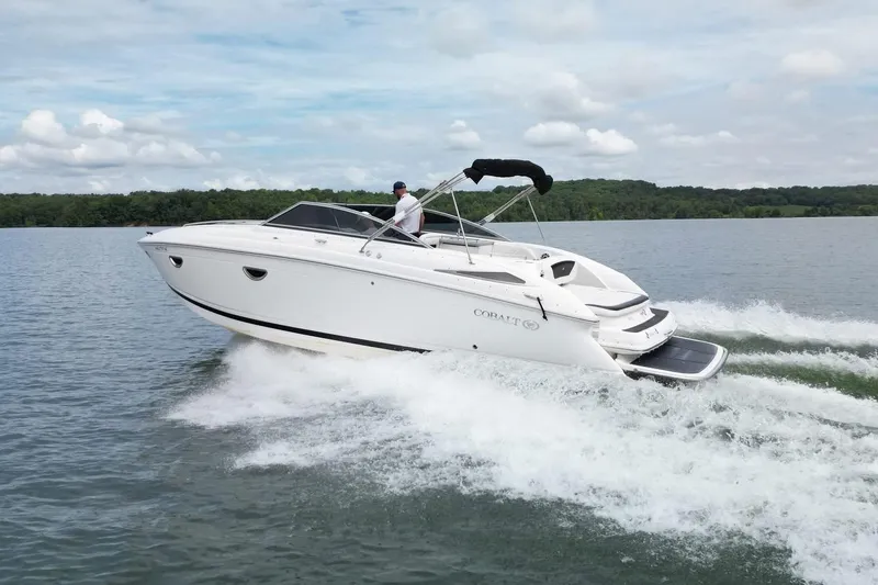 Slide: The Image of 2008 Cobalt 303 boat cruising on a lake with lush green shoreline. - 9