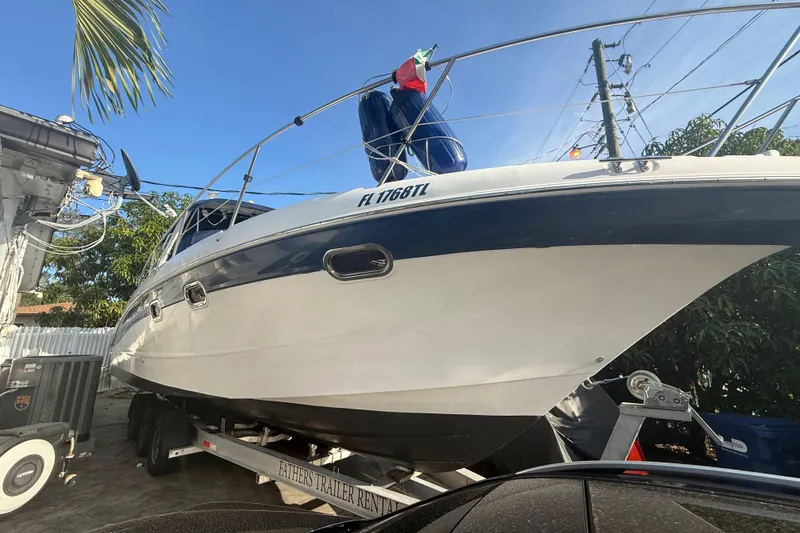 Slide: The Image of 2006 Four Winns 328 Vista boat on trailer, parked outdoors under clear blue sky. - 11