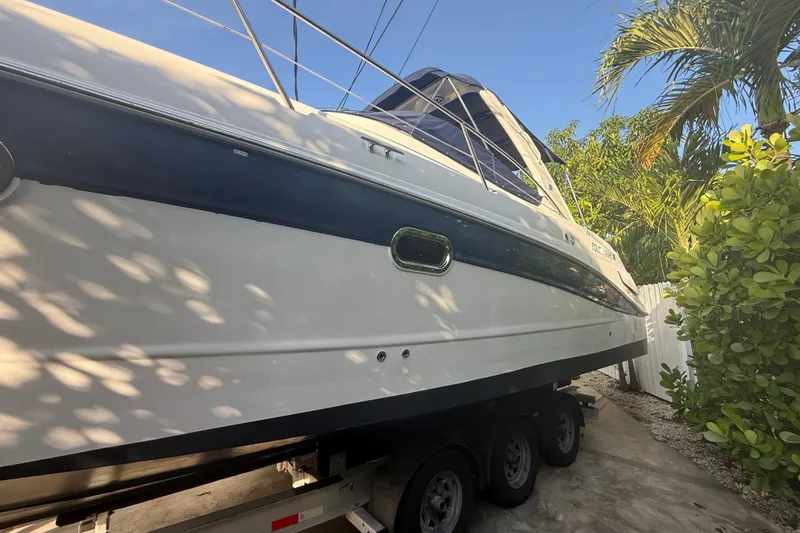 Slide: The Image of 2006 Four Winns 328 Vista boat on trailer, surrounded by tropical foliage. - 21