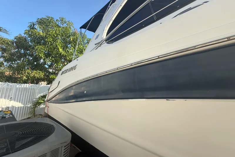 Slide: The Image of 2006 Four Winns 328 Vista boat side view, parked near trees and a fence. - 14