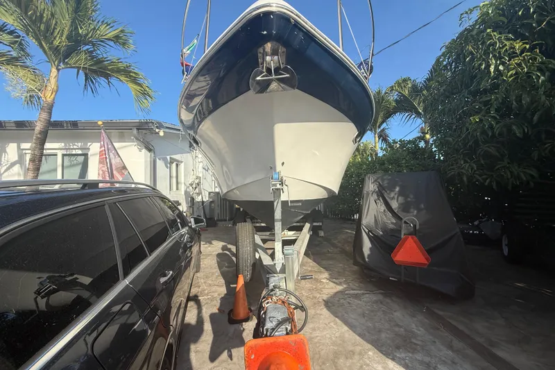 Slide: The Image of 2006 Four Winns 328 Vista boat on trailer, parked beside a car, surrounded by palm trees. - 5