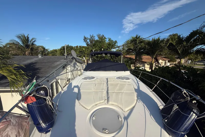 Slide: The Image of 2006 Four Winns 328 Vista boat docked near tropical trees and houses under clear blue sky. - 66