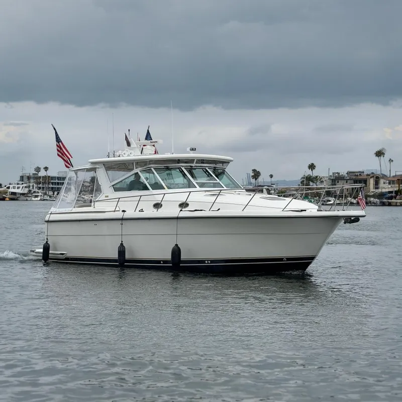 The Image of 2004 Tiara Yachts 4000 Express cruising on calm waters with American flags displayed. - 0