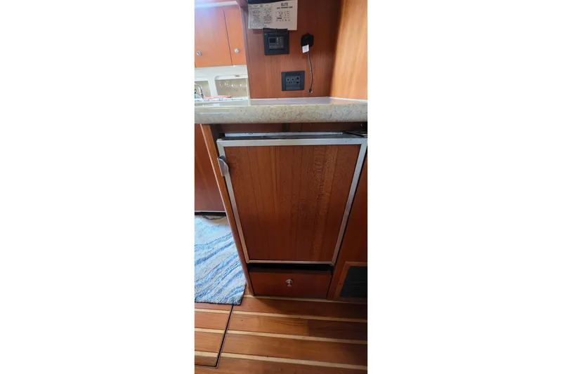Slide: The Image of 2004 Tiara Yachts 4000 Express interior with wooden cabinetry and compact refrigerator. - 13