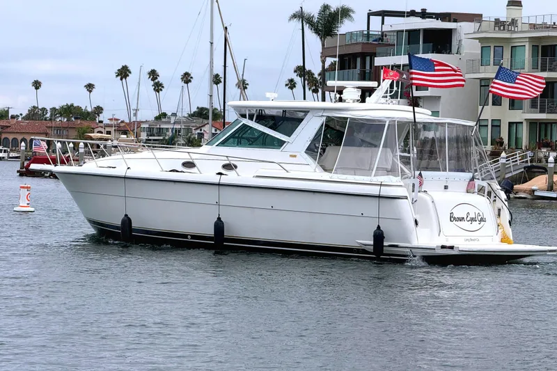 Slide: The Image of 2004 Tiara Yachts 4000 Express cruising in a marina with American flags displayed. - 3
