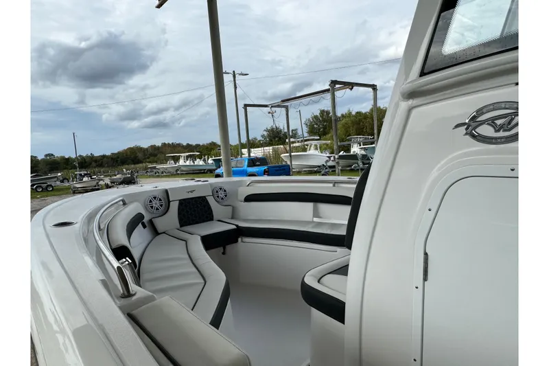 Slide: The Image of 2023 Tidewater 232 LXF boat interior with seating and speakers, under a cloudy sky. - 3