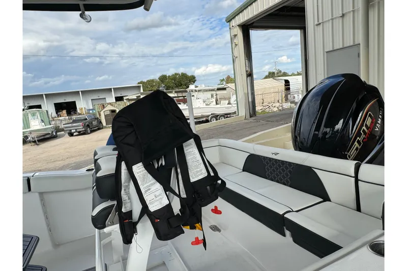 Slide: The Image of 2023 Tidewater 232 LXF boat interior with life jacket and Yamaha engine in a marina setting. - 5
