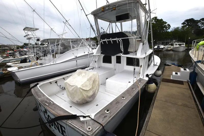 Slide: The Image of 1981 Blackfin 32 Sportfisherman docked at marina, featuring fishing rods and covered equipment. - 2