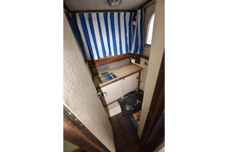 Slide: The Image of 1981 Blackfin 32 Sportfisherman cabin interior with striped curtain and compact sink area. - 9