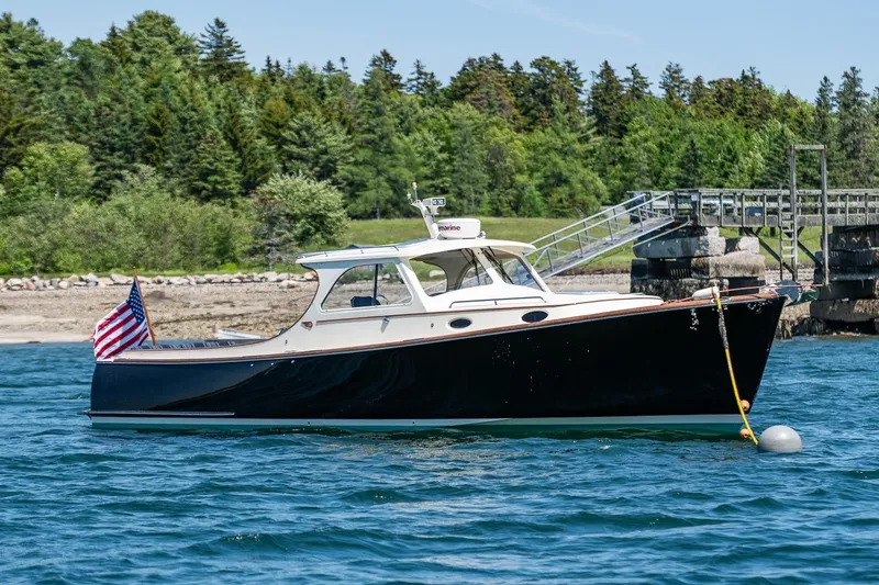 Slide: The Image of 2001 Hinckley Picnic Boat 36 Classic moored on calm water near a wooded shoreline. - 1