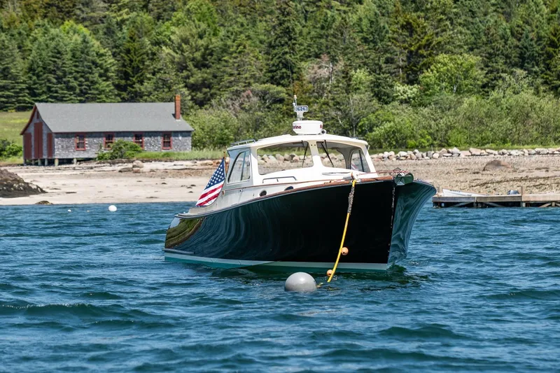 Slide: The Image of 2001 Hinckley Picnic Boat 36 Classic moored near a rustic shoreline cabin. - 2