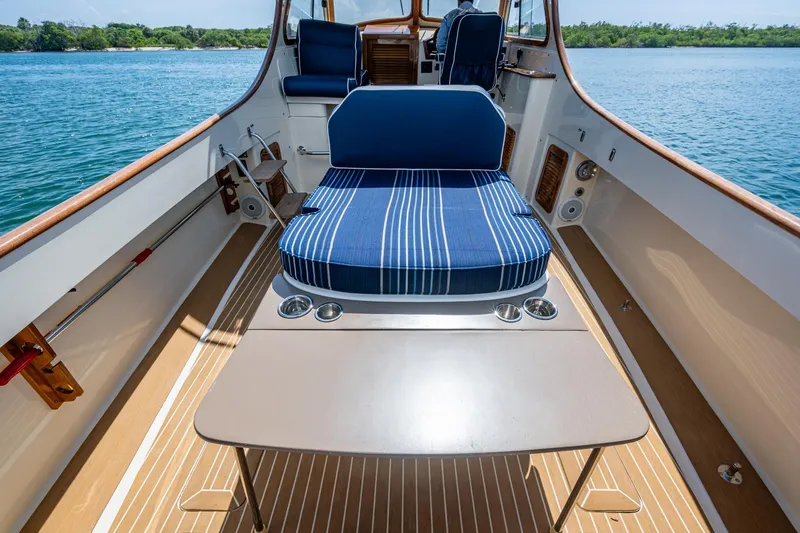 Slide: The Image of 2001 Hinckley Picnic Boat Classic interior with striped seating and table on calm water. - 21