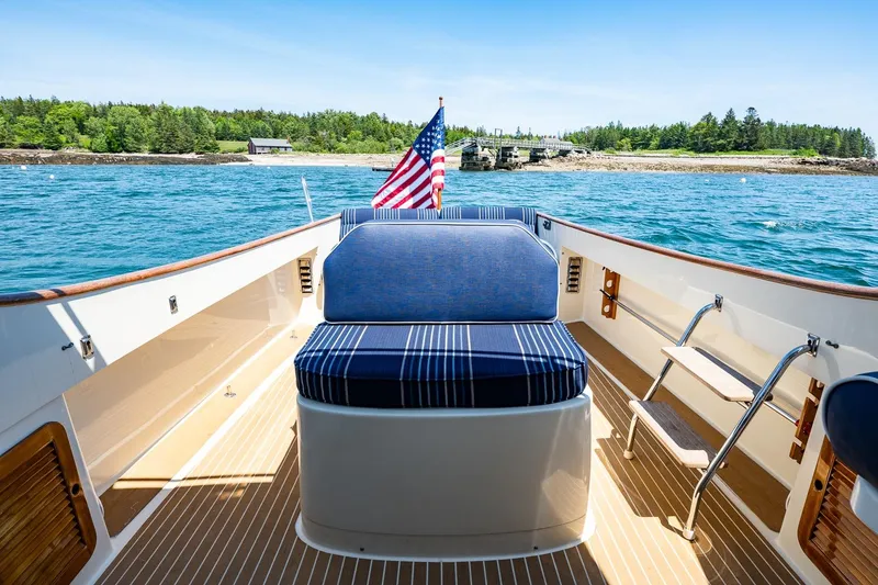 Slide: The Image of 2001 Hinckley Picnic Boat 36 Classic on water, featuring striped seating and American flag. - 24