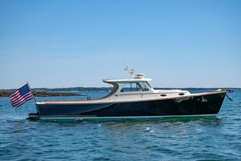 Slide: The Image of 2001 Hinckley Picnic Boat 36 Classic on calm water, displaying American flag. - 37