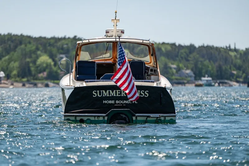 Slide: The Image of Hinckley Picnic Boat 36 Classic, 2001, on water with American flag, scenic background. - 38