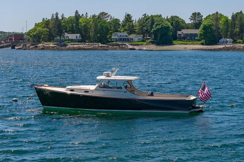 Slide: The Image of 2001 Hinckley Picnic Boat 36 Classic on serene water with coastal backdrop. - 6