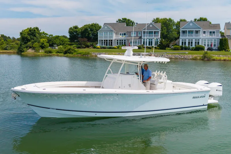 The Image of 2019 Regulator 31 boat cruising on a serene lake with waterfront homes in the background. - 0