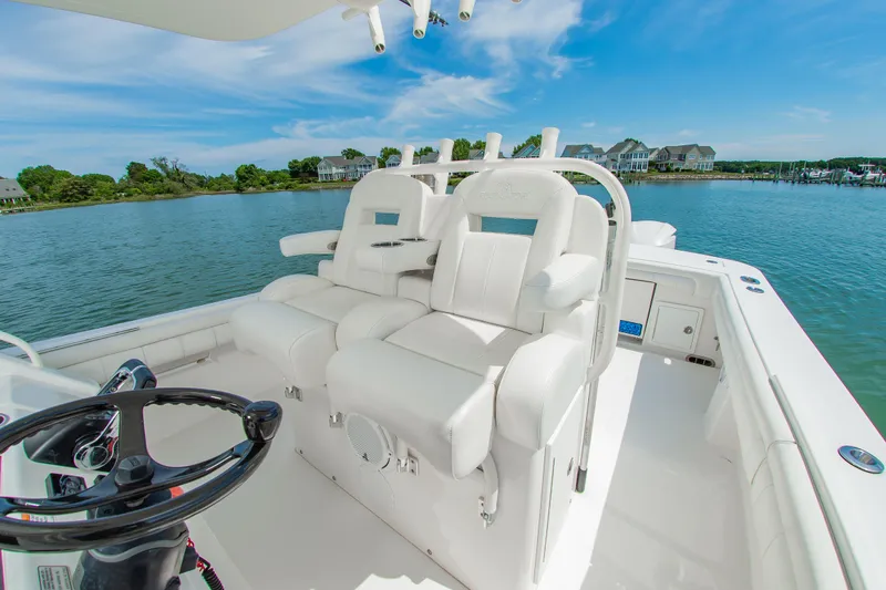 Slide: The Image of 2019 Regulator 31 boat interior with white seating, steering wheel, and scenic waterfront view. - 16