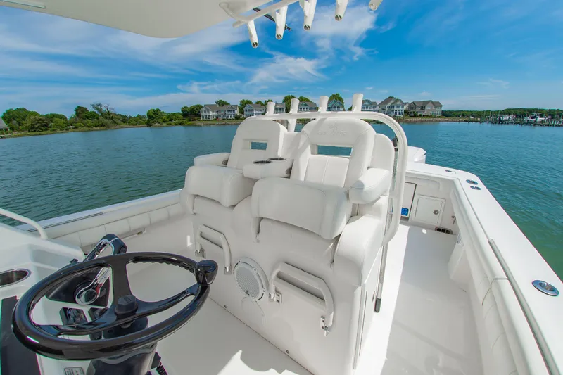 Slide: The Image of 2019 Regulator 31 boat interior with helm and seating, overlooking serene waterfront homes. - 17