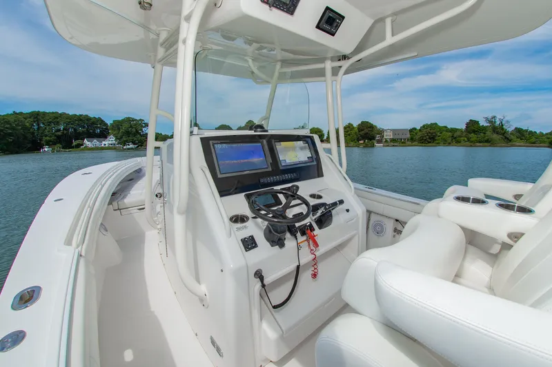 Slide: The Image of 2019 Regulator 31 boat cockpit with dual screens and steering wheel on a calm lake. - 19