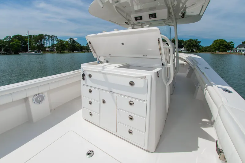 Slide: The Image of 2019 Regulator 31 boat with open storage compartments on a calm lake. - 23