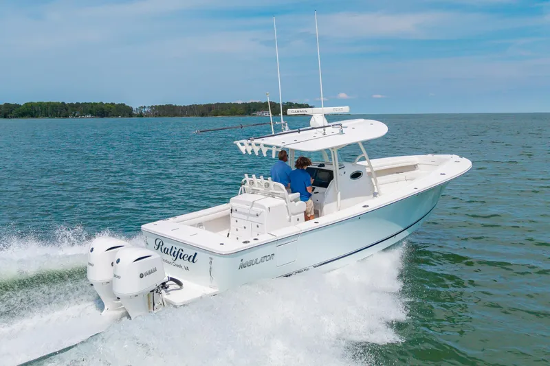Slide: The Image of 2019 Regulator 31 boat cruising on open water with twin Yamaha engines. - 46