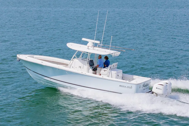 Slide: The Image of 2019 Regulator 31 boat cruising on open water with two people onboard. - 48