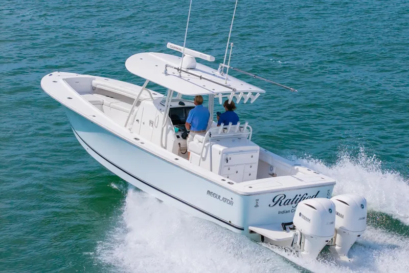 Slide: The Image of 2019 Regulator 31 boat cruising on open water with twin Yamaha engines. - 52