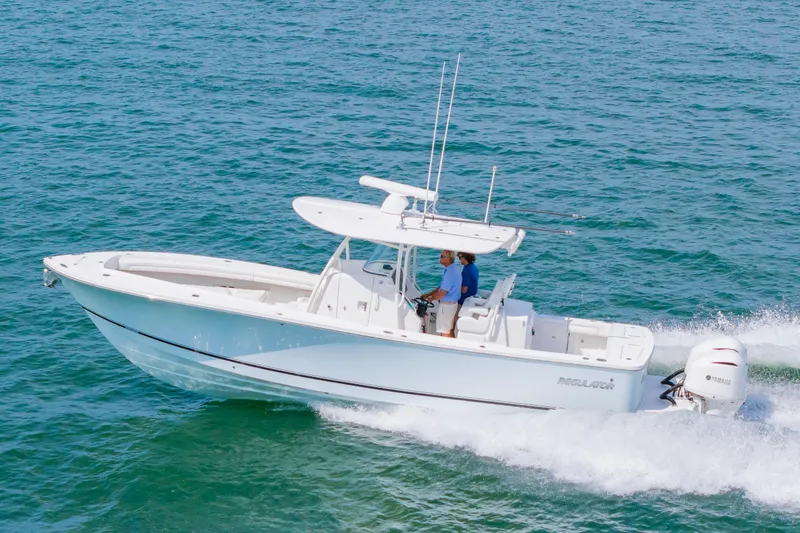 Slide: The Image of 2019 Regulator 31 boat cruising on open water with two people onboard. - 57