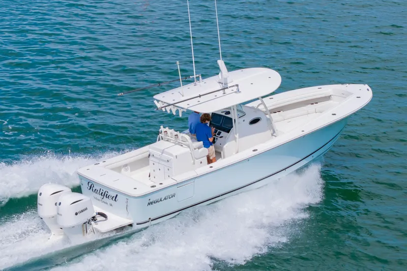 Slide: The Image of 2019 Regulator 31 boat cruising on open water with twin Yamaha engines. - 59