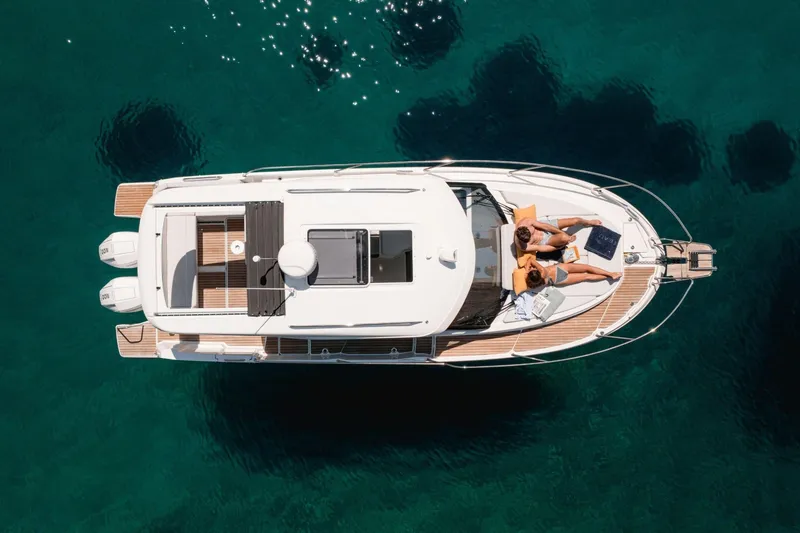 Slide: The Image of 2027 Beneteau Antares 9 yacht with sunbathers on deck, floating in clear blue water. - 2