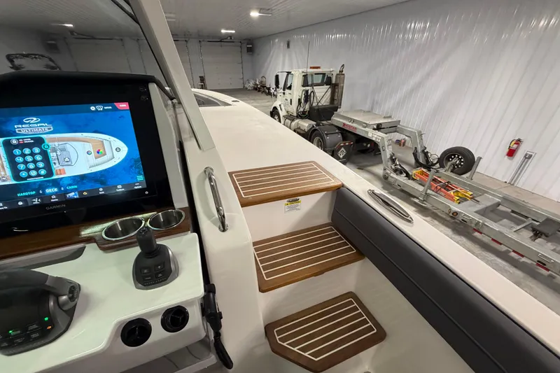 Slide: The Image of 2027 Regal 38 Surf boat interior with control panel and wooden steps in a garage. - 35