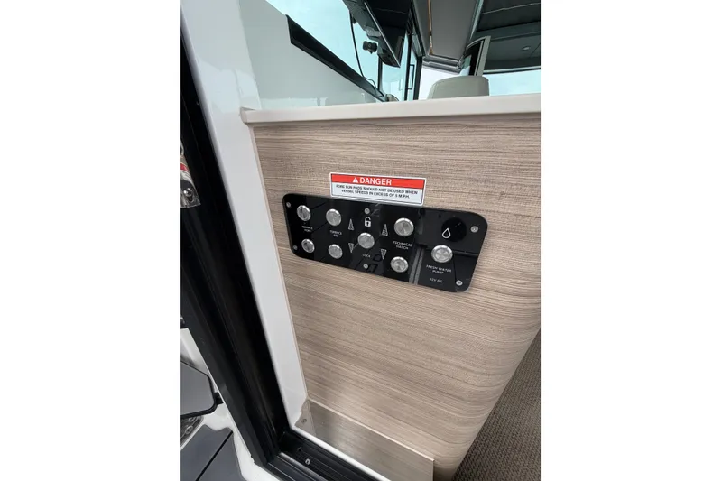 Slide: The Image of Control panel on 2025 Saxdor 320 GTC boat, featuring various switches and warning label. - 32