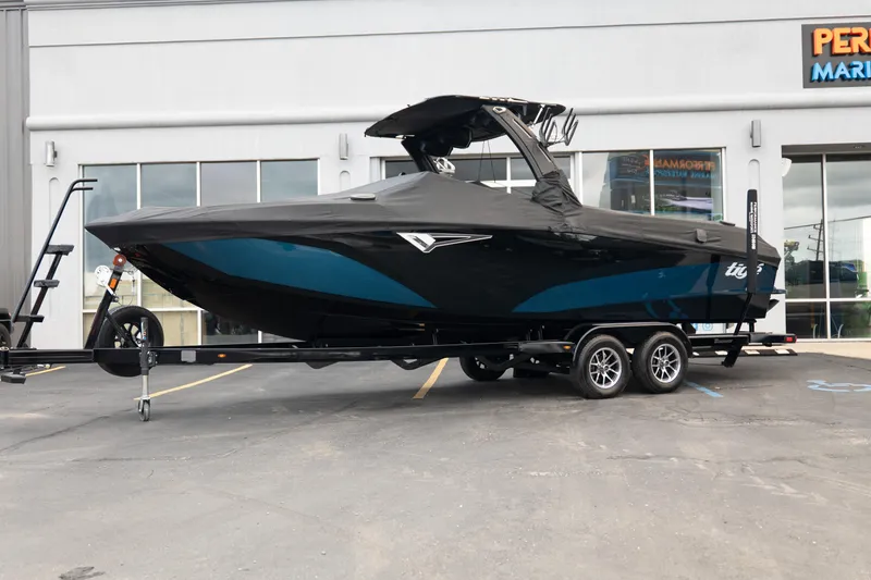 Slide: The Image of 2024 Tigé Z5 boat with cover on trailer, parked outside a marine store. - 37