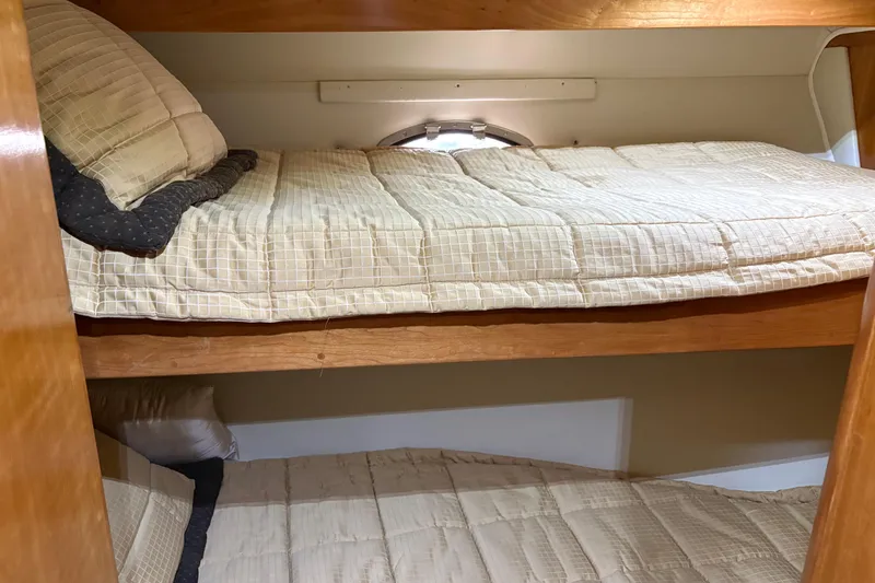 Slide: The Image of Bunk beds in 2001 Navigator Yacht 5600 Pilothouse Classic, featuring cozy bedding and wooden frames. - 27