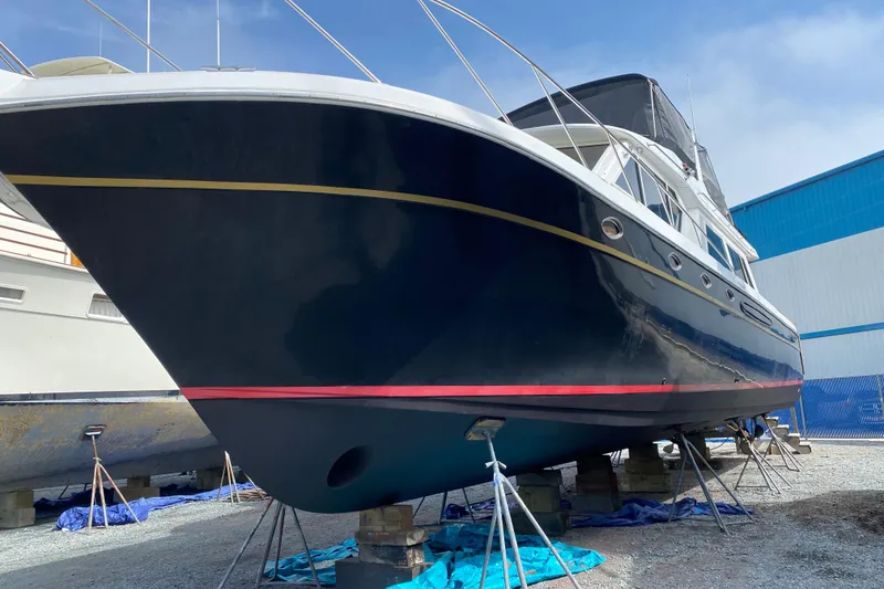 Slide: The Image of 2001 Navigator Yacht 5600 Pilothouse Classic on dry dock, blue hull, red stripe. - 4