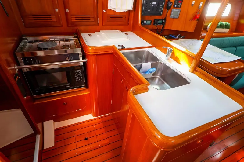 Slide: The Image of Galley of 2002 Beneteau Oceanis Clipper 361 with stove, sink, and wooden cabinetry. - 49