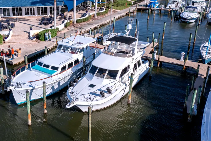 Slide: The Image of 1967 Huckins Linwood 53 yacht docked at marina, surrounded by other boats and waterfront dining. - 4