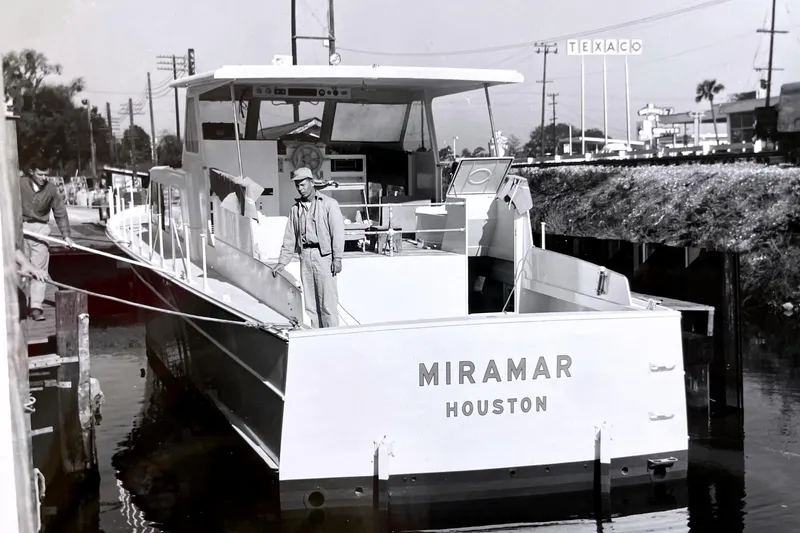 Slide: The Image of 1967 Huckins Linwood 53 yacht "Miramar" docked, with crew member on deck, Texaco sign visible. - 3