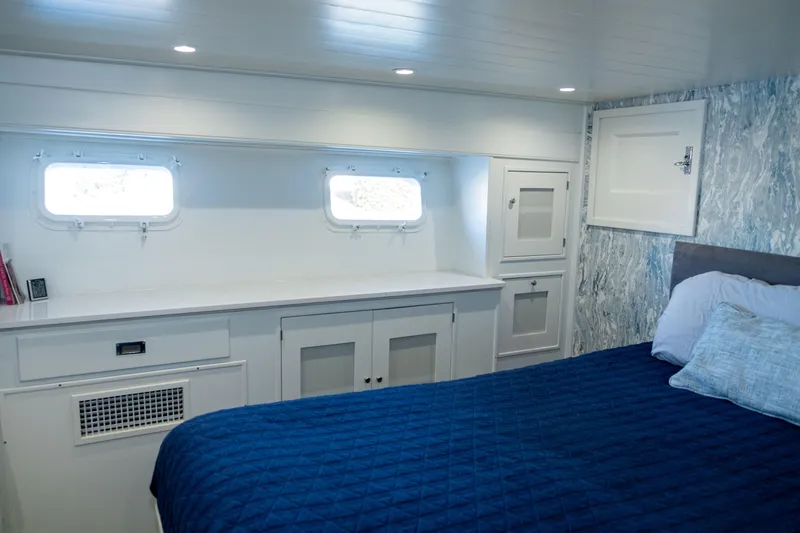 Slide: The Image of Interior cabin of 1967 Huckins Linwood 53 yacht with blue bedding and white cabinetry. - 22