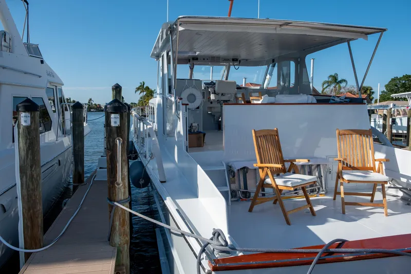Slide: The Image of 1967 Huckins Linwood 53 yacht docked, featuring wooden chairs on deck under clear blue sky. - 5